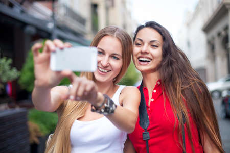 Close up lifestyle portrait of girls best friends makes funny grimaces on camera laughing together.Two women posing outdoorの写真素材