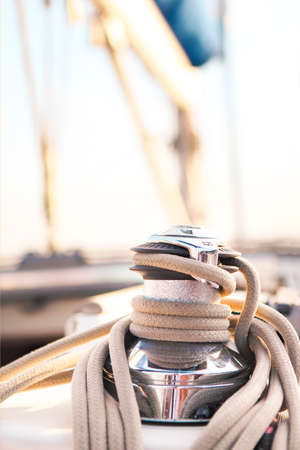 Sailboat detailed parts. Close up on winch and rope of yacht over blue sea. Yachting concept. Shallow depth of fieldの写真素材