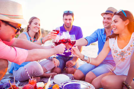 People holding glasses of red wine making a toast at the beach picnicの写真素材
