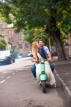 Happy young couple by a vintage scooter on the street. Holiday and travel conceptの写真素材