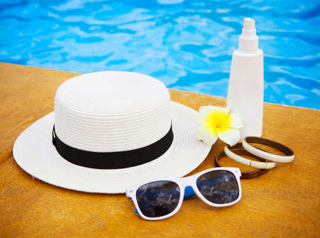 Suncream, sunglasses, hat, bracelet near the swimming pool. Vacation conceptの写真素材