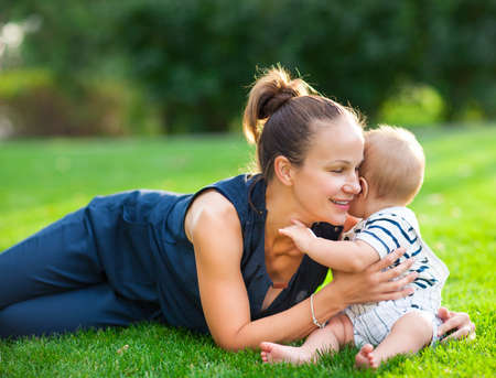 Happy mum and her child playing in park together. Outdoor portrait of happy family