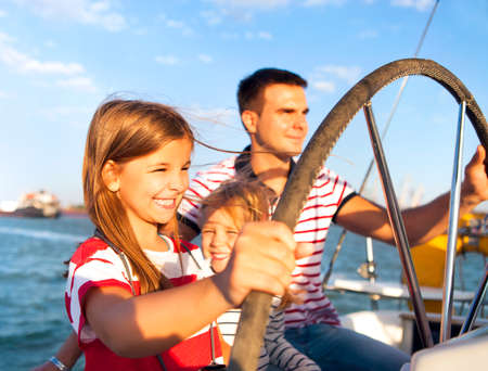Young father with adorable daughters resting on a big boatの写真素材