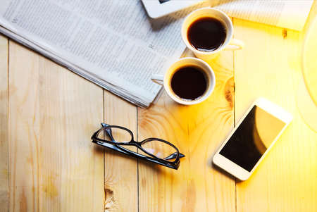 Black coffee with blank digital tablet and mobile phone, magazines and glasses on the table. Break conceptの写真素材
