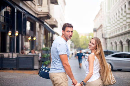 Happy couple in love walking in Tbilisi city, Georgia. Young adults tourists on travel