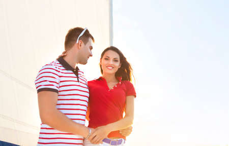 Young smiling couple on a sailing boat at summer sunsetの写真素材