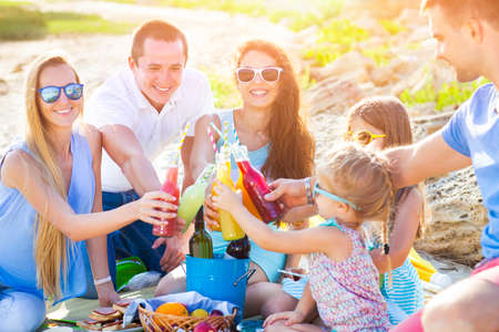 Friends sitting on the sand at the beach at the summer picnic with lemonadeの写真素材