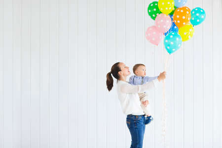Little boy with his mom holding a large bunch of colored balloonsの写真素材