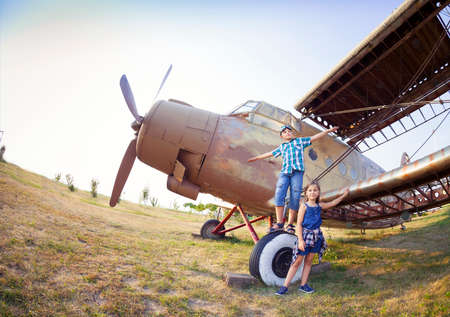 Little boy and little girl pilot near the retro airplane at the airportの写真素材