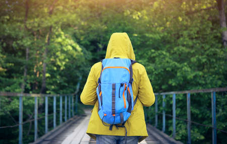 Tourist man walking across wooden bridge over mountain riverの写真素材