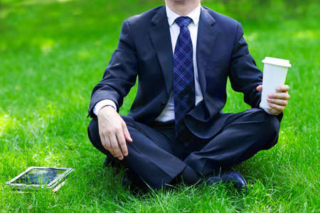 Close up of the hands of the businessman with a tablet PC and coffee. Outdoorsの写真素材