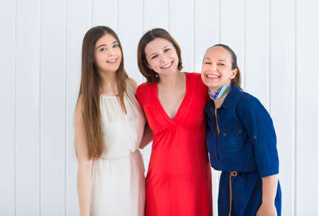 Happy female friends with pregnant woman on white backgroundの写真素材