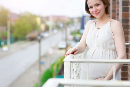 Beautiful happy pregnant woman on the balconyの写真素材