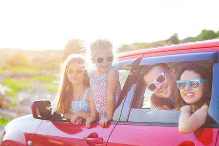 Portrait of a smiling family with two children at beach in the car. Holiday and travel conceptの写真素材