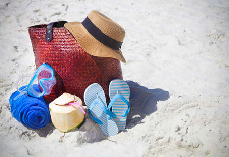 Straw hat, wather mask, beach towel, flip flops with beach bag and coconut cocktail. Summer travel...