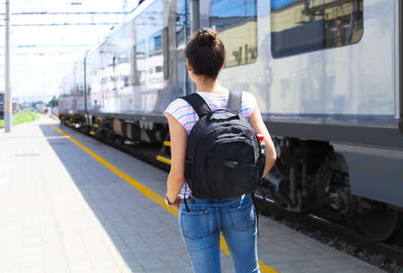Travel concept. Young woman with backpack on train station. Rear view.