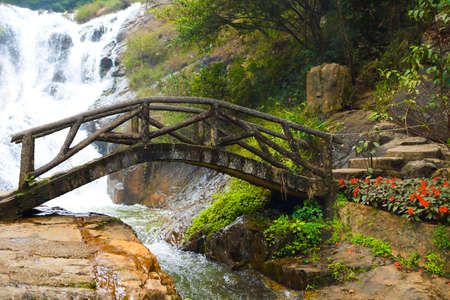 Wooden bridge in the mountain forest close to waterfall.の写真素材