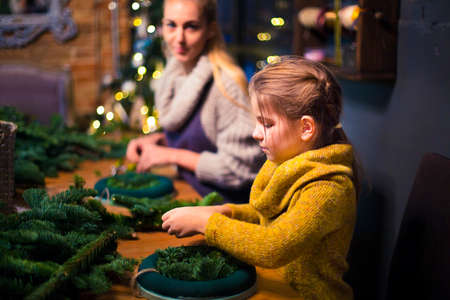 Mother and daughter decorating coniferous wreath. Christmas celebration conceptの写真素材