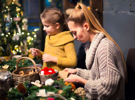Mother and daughter decorating coniferous wreath. Christmas celebration conceptの写真素材