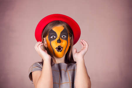 Pretty girl with face painting of a pumpkin. Halloween themeの写真素材