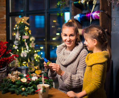 Mother and daughter decorating coniferous wreath. Christmas celebration conceptの写真素材