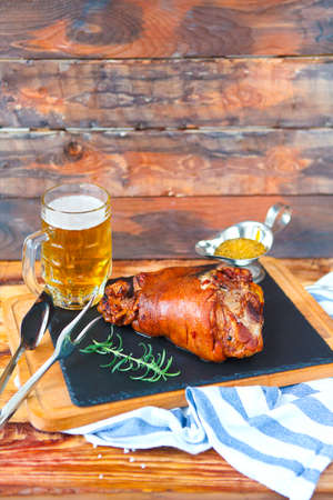 Roasted pork leg (rulka) served with garlic sauce and beer on the wooden tableの写真素材