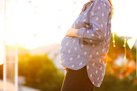 Pregnant woman against the backdrop of the city in the eveningの写真素材