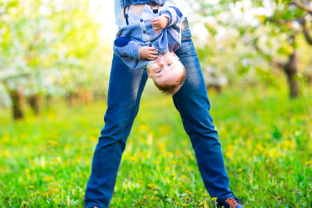 Little baby boy with his young mother in the blossoming spring garden