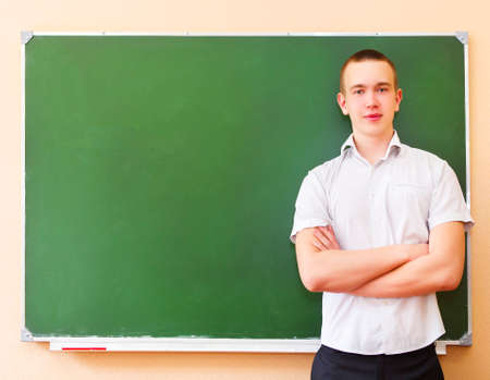 Student boy standing near the blackboard in the classroomの写真素材