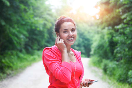 Brunette young woman jogging and listening to music outdoors.の写真素材
