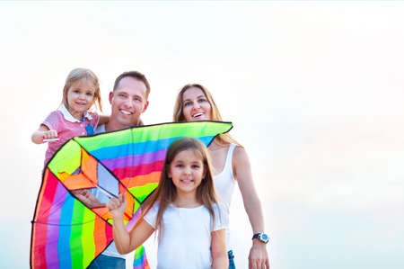Happy young smiling family with flying a kite on the beachの写真素材