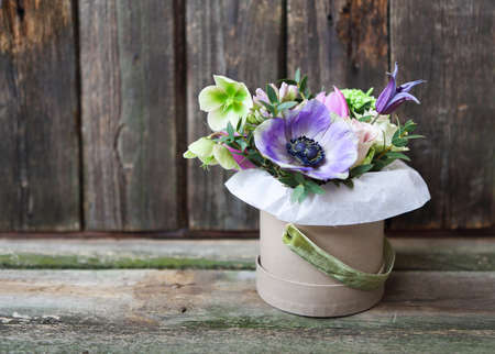 Bouquets of pink and violet flowers in the box on a woden background, close up の写真素材