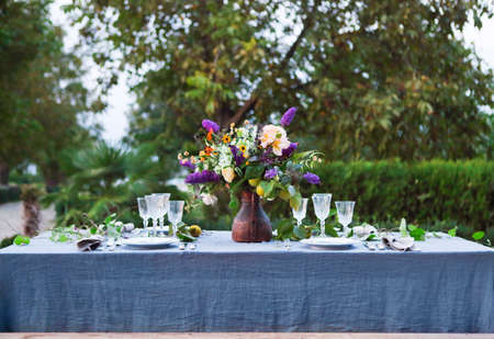 Bouquet of pink, violet and yellow flowers on a table set for dinner, close up の写真素材