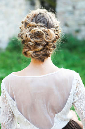 Back view of unrecognizable young woman with blond hair in white wedding dress and wreath over...