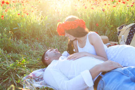 Young couple in love kissing and hugging at poppy fieldの写真素材