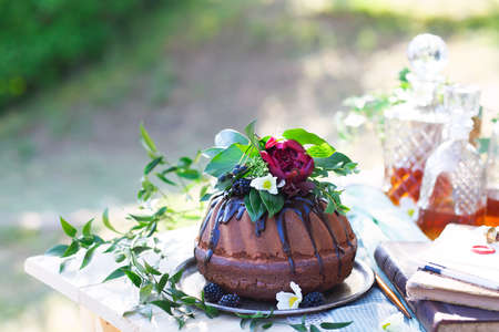Cocolate cake decorated with flowers and three whiskey decanters against a light gray background with copy spaceの写真素材
