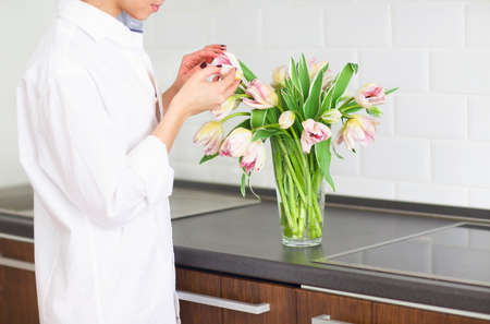 Woman arranging floral bouquet in a kitchen. Close upの写真素材