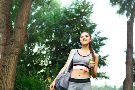 Young happpy woman walking in the park after sport activity with detox drinkの写真素材