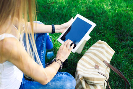 Table pc in a hand of girl on a background a green grass