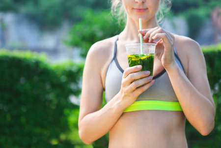 Young fitness athlete woman resting drinking organic herbs and fruits drink outdoorsの写真素材
