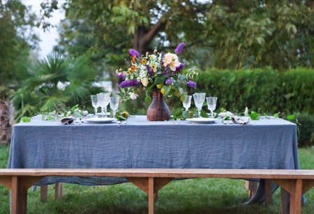 Bouquet of pink, violet and yellow flowers on a table set for dinner, close upの写真素材
