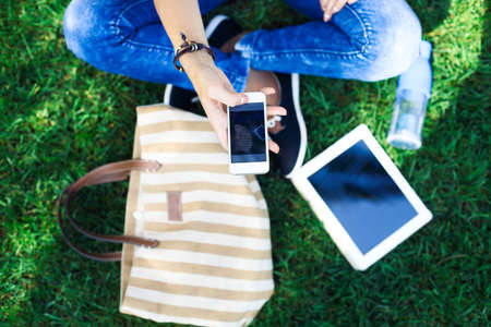 Mobile phone in a hand of girl on a background a green grass