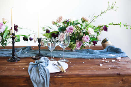 Bouquets of pink flowers on a table set for dinner with candles, close upの写真素材