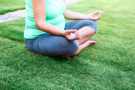 Beautiful pregnant woman meditaiting in summer park. Pregnant yogaの写真素材