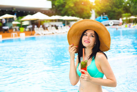 Real female beauty enjoying her summer vacation at swimming pool with alcohol cocktail