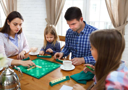 Happy young family plaing board game with two daughtersの写真素材