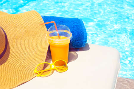 Swimming pool, orange juice, beach towel, sunglasses on sun bed. Summer vacation conceptの写真素材