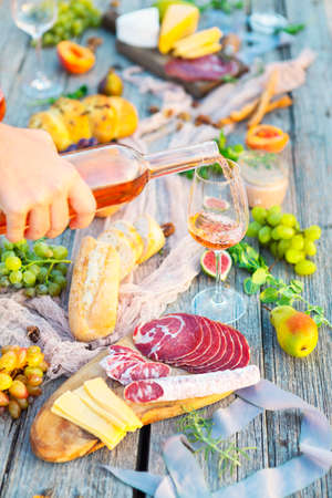 Picnic outdoor rose with wine fruits meat and cheeseの写真素材