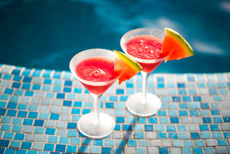 Glasses of watermelon cocktail with watermelon slices near the pool