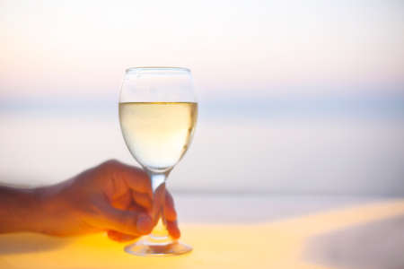 Relaxing man with glass of white wine in the beach bar. Close upの写真素材